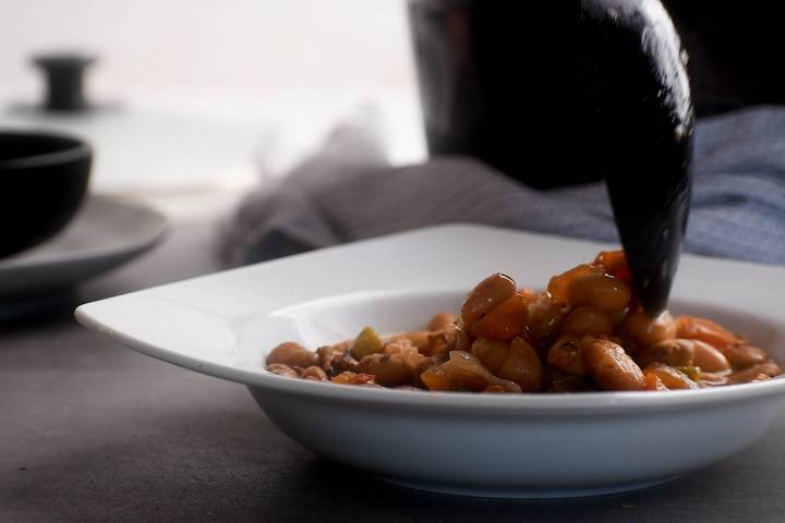 Charro beans being served in a bowl with a spoon.