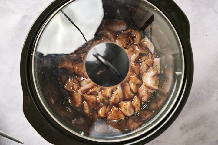 Chicken breast chunks in a slow cooker covered in honey garlic sauce.