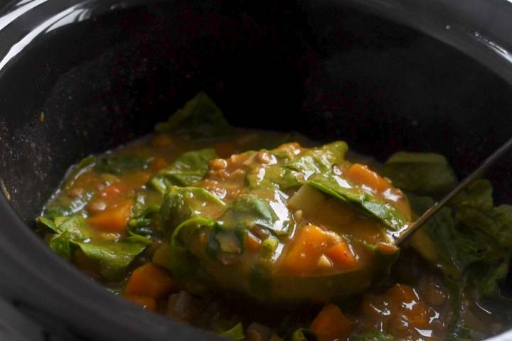 Lentil soup in a slow cooker with a ladle.