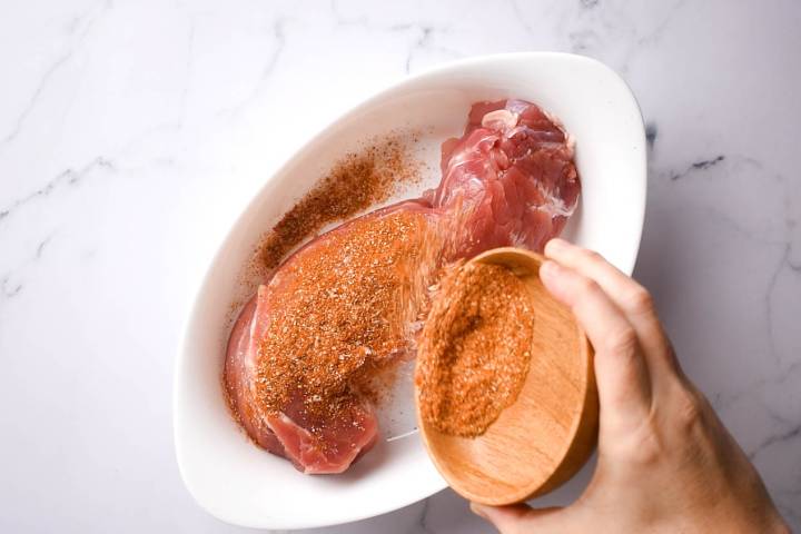 Pork tenderloin being coated in a spice rub.