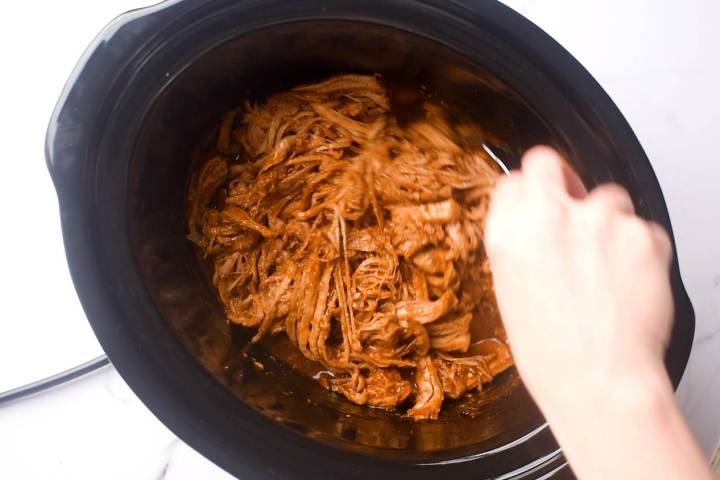 Shredded spicy pulled pork in a slow cooker.