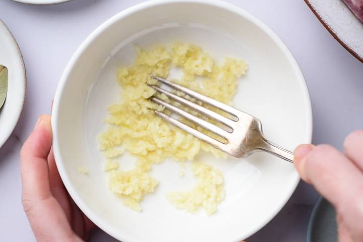 Garlic cloves being mashed into a paste.