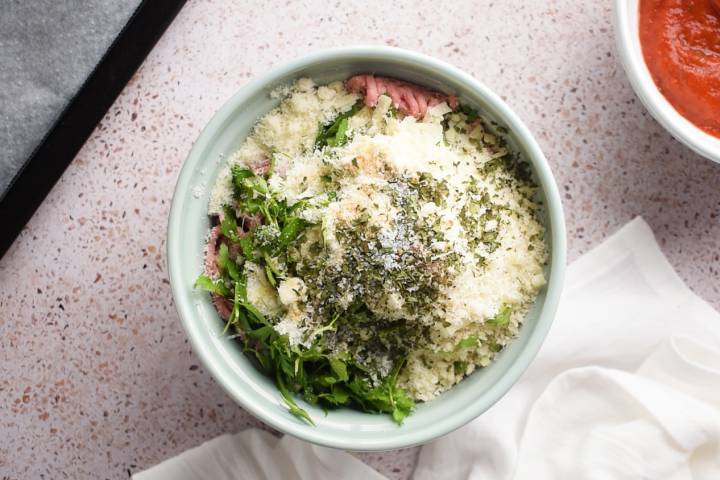Ingredients for turkey meatballs in a bowl including breadcrumbs, parmesan cheese, and parsley.