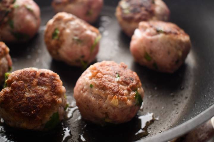 Turkey meatballs being seared in a hot pan.
