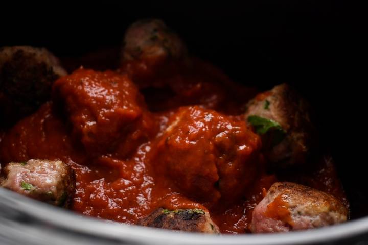 Turkey meatballs cooking in a slow cooker with tomato sauce.