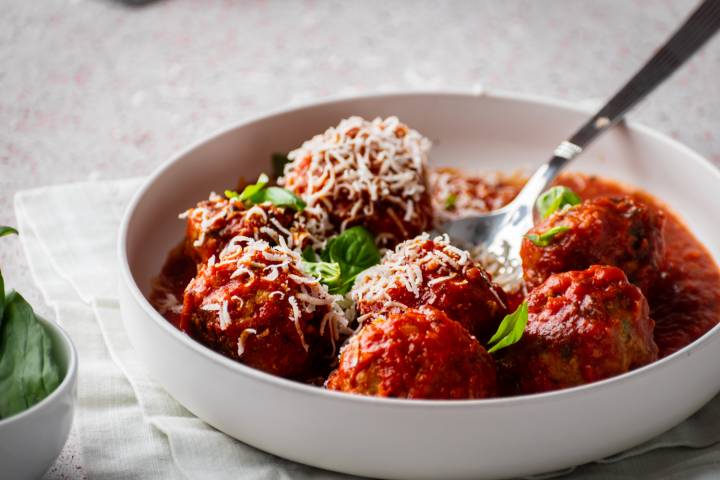 Turkey meatballs being served with marinara sauce in a bowl.