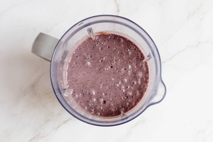 Blueberries, bananas, spinach, almond milk, flax, and chia seeds in a blender.