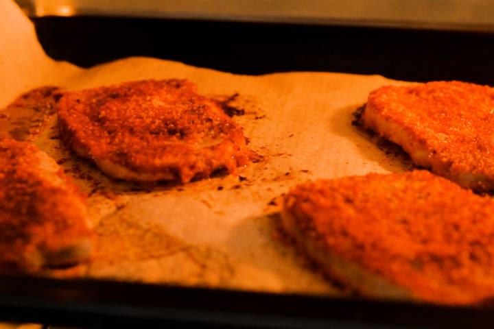 Spice crusted pork chops cooking in the oven.