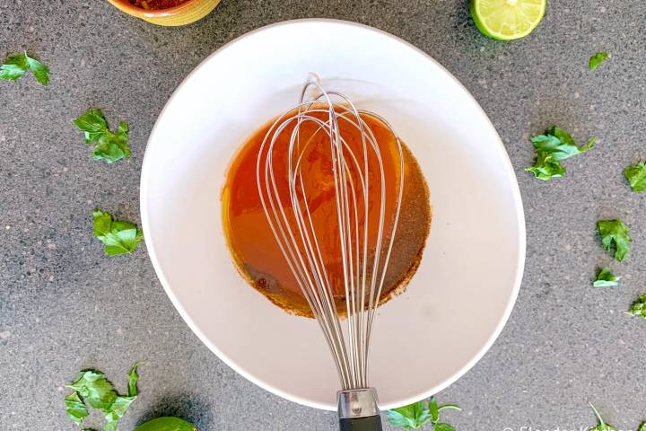 Spicy marinade for grilled chicken in a bowl with a whisk.