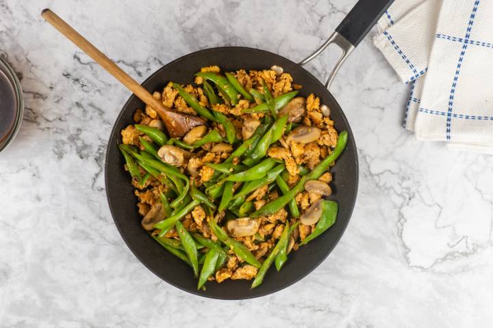 Ground turkey, mushrooms, and green beans in stir fry sauce in a skillet.