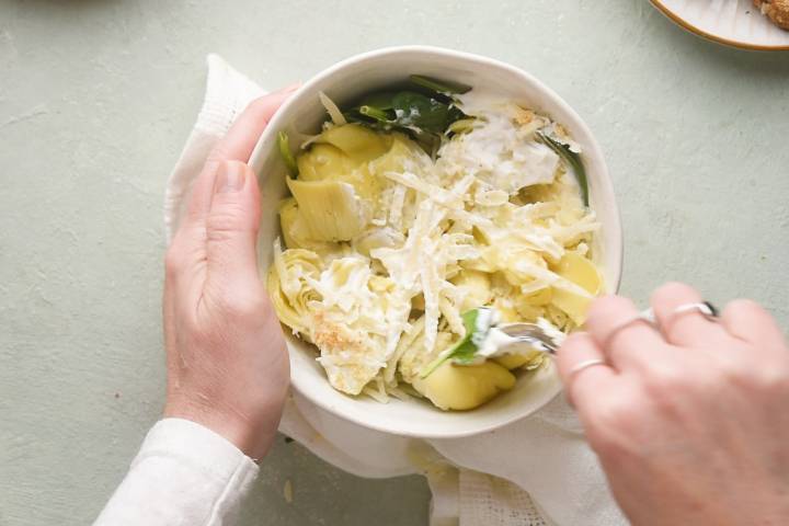 Spinach, artichoke hearts, cream cheese, and mozzarella cheese in a bowl.