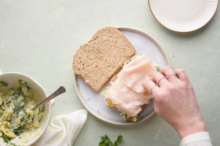 Wheat bread with a spinach artichoke mixture and turkey on a plate.