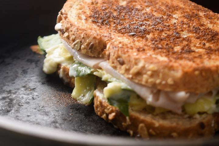 Spinach artichoke grilled cheese cooking in a skillet.