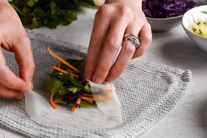 Spring roll being folded and rolled.