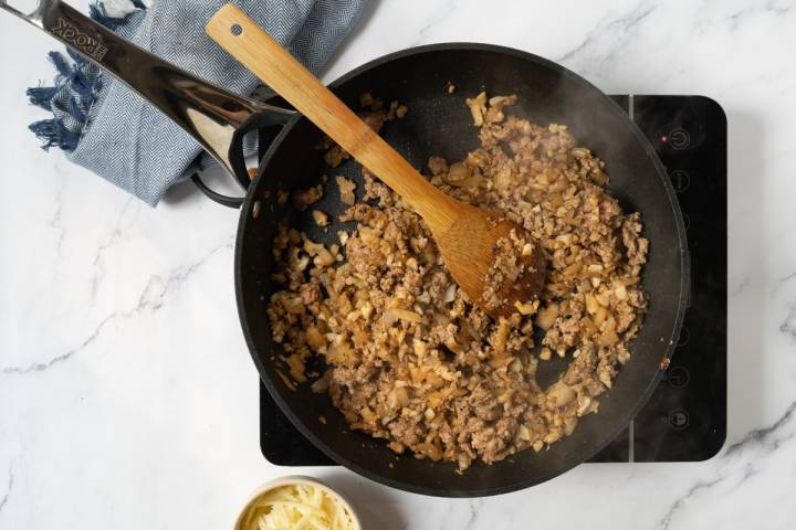 Ground turkey and cauliflower with onions and taco seasoning in a skillet.