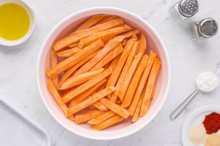 Sliced sweet potatoes soaking in a bowl of cold water.