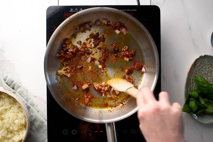 Onions, garlic, ginger, and curry paste cooking in a skillet.