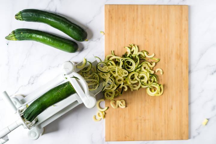 Zucchini being turned into noodles with a spiralizer.