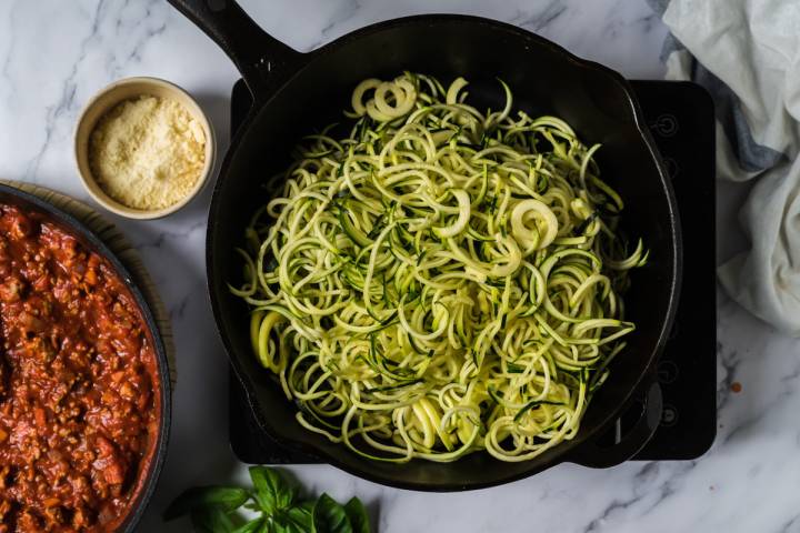 Zucchini noodles cooking in olive oil in a skillet.
