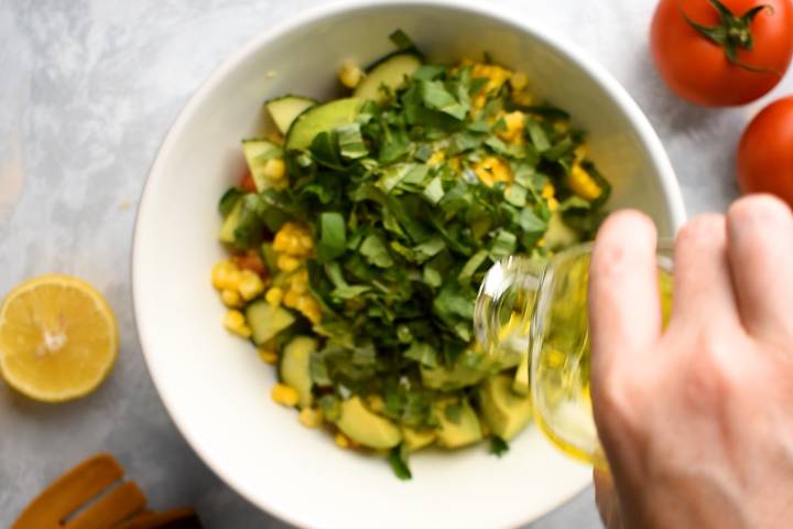 Salad dressing being added to a tomato and cucumber salad.