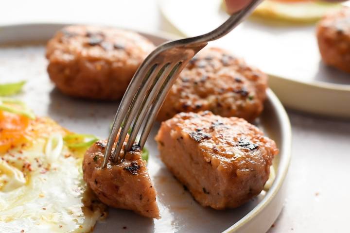 Fork taking a bite of a cooked turkey breakfast sausage.