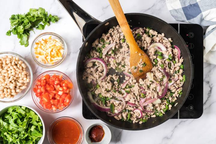 Ground turkey and poblano peppers cooking in a skillet.
