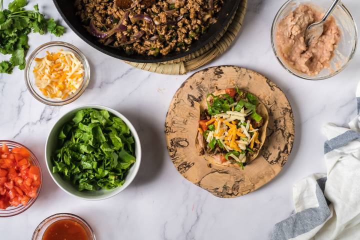 Turkey poblano tostadas being assembled on a baked corn tortilla.