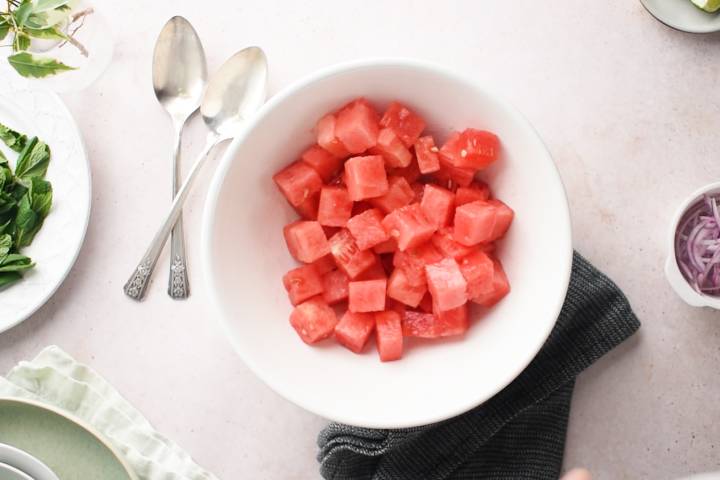 Cubed watermelon in a white bowl.
