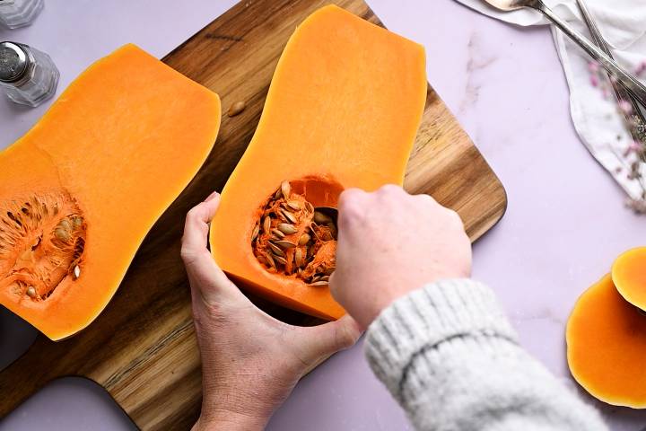 Seeds being scooped out of a butternut sqaush.
