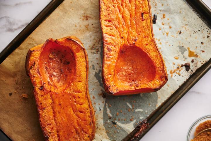 Roasted butternut squash with salt and pepper on a baking sheet.