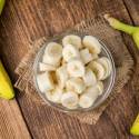 Bananas sliced and served in a bowl with fresh bananas on the side.