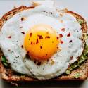 Eggs on a piece of toast with avocado and red pepper flakes.
