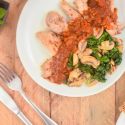 Balsamic chicken thighs with spinach and mushrooms on a plate with a napkin, fork, and knife.