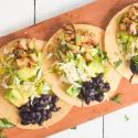 Black bean and zucchini tacos with avocado and cabbage slaw on corn tortillas.