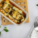Eggplant rollatini with mozzarella cheese in a casserole dish with fresh basil.