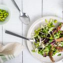 Chinese Chicken Salad with sesame dressing, chicken, edamame, and cabbage on a plate with a fork and spoon.