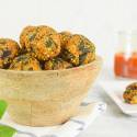 Quinoa meatballs with spinach in a bowl with basil and marinara sauce on the side.