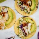 Fish tacos with lime coleslaw on corn tortillas with avocado.
