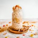Apple cinnamon overnight oats in a glass jar with cooked apples and cinnamon on top.
