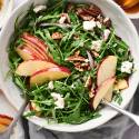 Arugula apple and goat cheese salad with pecans and lemon dressing in a bowl.