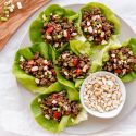 Asian ground beef lettuce wraps served on a plate with beef, mushrooms, peppers, and cashews wrapped in butter lettuce.