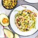 Avcoado zucchini noodles with shrimp and corn served on a plate with lime.