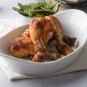 Baked chicken drumsticks with a paprika spice rub served in a white dish with vegetables on the side.