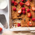 Baked oatmeal made with rolled oats in a baking dish with raspberries, strawberries, and chocolate chips.