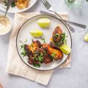 Blackened chicken breast with a crispy exterior on a plate with lime and cilantro.