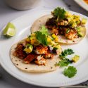 Blackened fish tacos with mango avocado salsa on corn tortillas with fresh cilantro and lime wedges.
