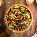 Blackened steak salad with thinly slcied steak over a bed of Romaine lettuce, red onion, peppers, and cheese.