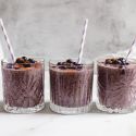 Blueberry banana smoothie with frozen bananas, blueberries, and spinach blended in a glass with blueberries on top. 
