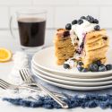 Blueberry lemon ricotta pancakes in a stack with with fresh blueberries and Greek yogurt.