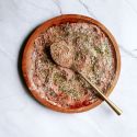 Cajun seasoning blend with smoked paprika, garlic powder, onion powder, oregano, and thyme on a wooden plate with a gold spoon.